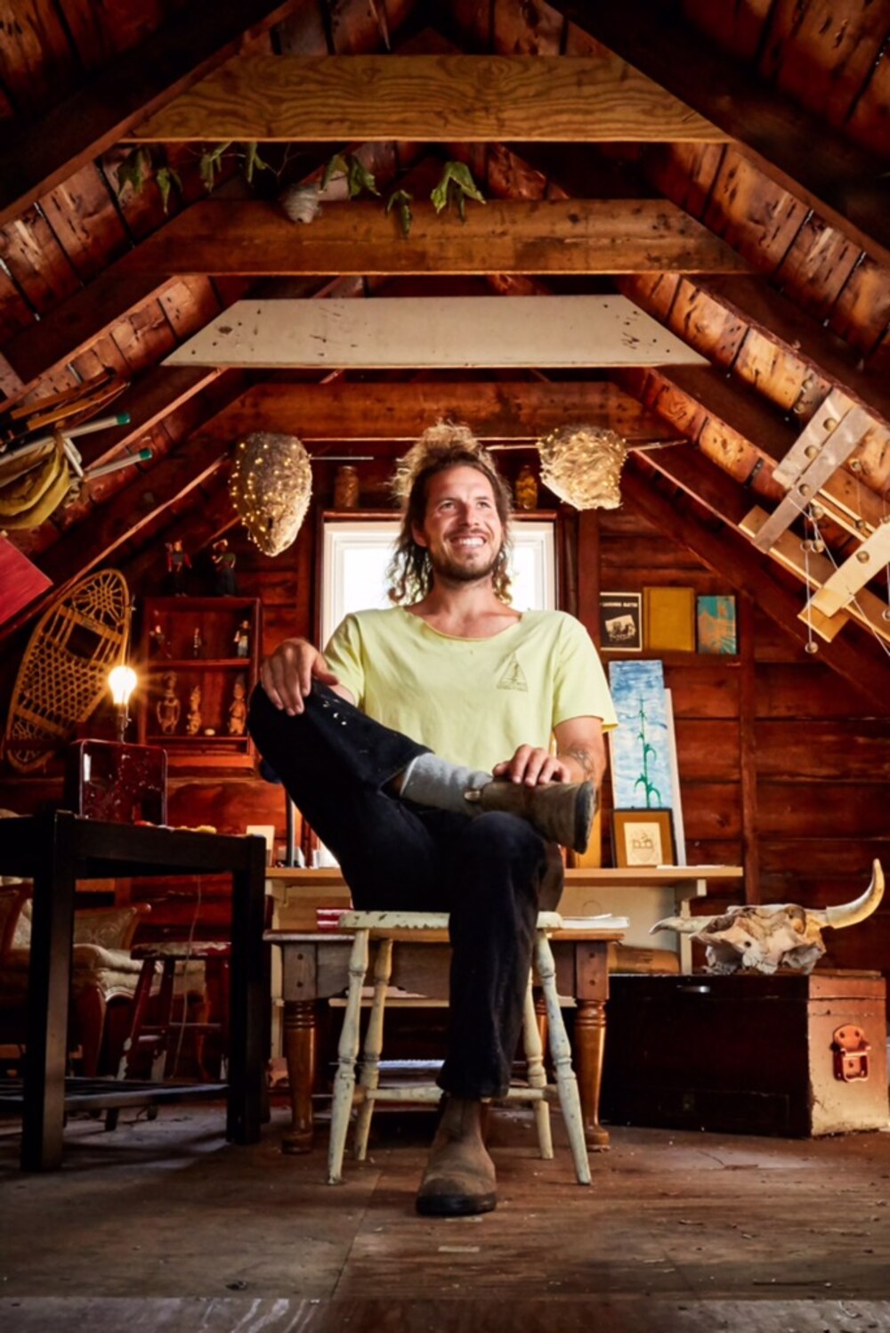 Carrier sitting in his wood-beamed studio, surrounded by tools and art.